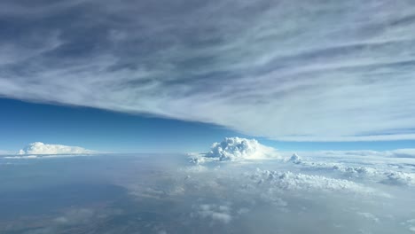 Impressive-Pilot-POV-while-flying-at-12000-metres-high-flying-between-layres-of-clouds-with-a-cumulus-ahead,-daylight