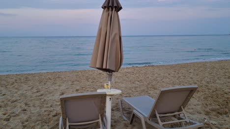 Empty-sunbeds-and-closed-umbrella-on-a-sandy-beach-in-the-evening-on-cloudy-day