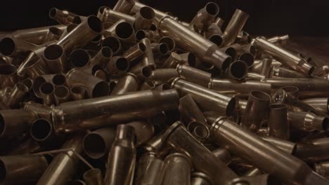Extreme-close-zoom-in-of-large-pile-of-bullet-cases-on-a-wooden-surface