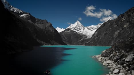 Drone-flying-over-a-blue-lake-Paramount-Pictures'-snow-capped-mountain-at-Laguna-Paron,-Huaraz,-Peru
