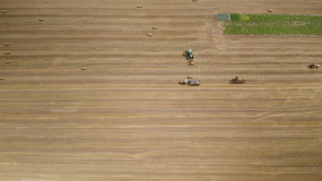 Hay-Harvest-Agriculture-Machinery,-Tractors-in-Agricultural-Farmland-Field-Working-Moving-Driving-to-Carry-Load-Hay-Bales,-Farm-Work-and-Harvesting-Aerial-View