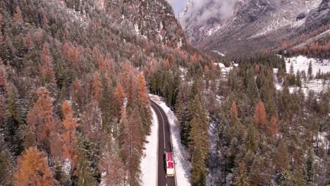 Road-passing-through-alpine-valley-with-woodland-landscape-during-winter,-aerial