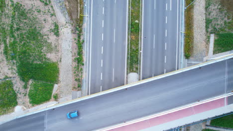 Aerial-top-down-shot-of-blue-car-on-bridge-road-crossing-in-daylight---Above-asphalt-highway