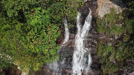 Ascending-aerial-shot-looking-down-on-a-waterfall-and-walking-trail-steps