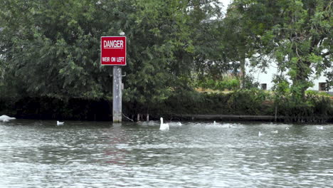 Red-warning-board-on-the-river-Thames-flowing-through-Royal-Windsor-in-England