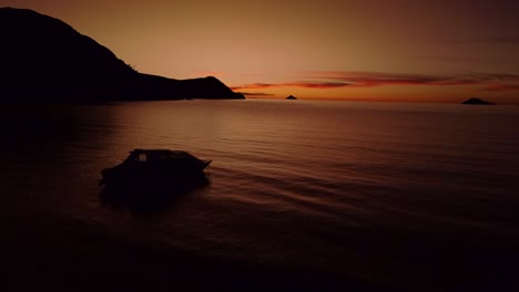 Langsame-Luftaufnahme-Eines-Dunkelorangefarbenen-Sonnenuntergangs-In-Der-Abenddämmerung-Mit-Einem-Boot-Auf-Dem-Titicaca-See-In-Peru