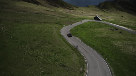 Car-drives-down-curvy-Giau-Pass-past-motorcycles-in-scenic-Dolomites