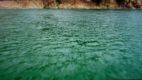 Aerial-cinematic-shot-over-turquoise-green-water-revealing-a-mountain-on-Lake-Quilotoa-in-Ecuador