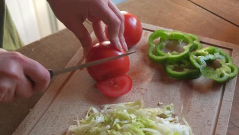 Cook-cutting-and-slicing-a-red-tomato-with-veggies-in-4K-slow-motion