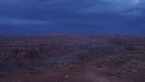 Cinematic-aerial,-van-life-mini-camper-van-parked-on-red-rock-sandstone-canyon-cliffs-of-Arizona