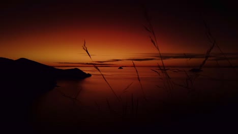 Schöner-Dunkeloranger-Sonnenuntergang-Mit-Pflanzen-Im-Vordergrund-Am-Titicacasee-In-Peru