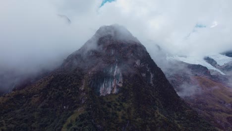 Circular-aerial-shot-of-a-mountain-peak-with-vegetation-on-a-foggy-day-in-the-Andes