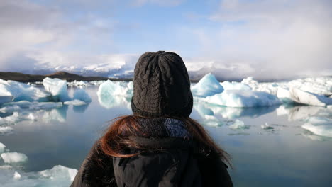 Toma-Cinematográfica-De-Una-Mujer-Disfrutando-Del-Paisaje-Y-Los-Pequeños-Icebergs-Que-Se-Encuentran-En-El-Parque-Nacional-Jökulsárlón-En-Islandia