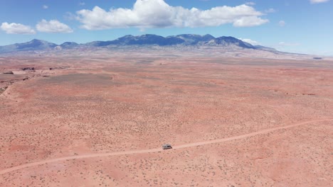 Aerial,-camper-mini-van-on-a-road-trip-driving-on-sandstone-desert-road-in-Utah