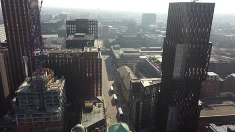 Aerial-drone-flight-along-Oxford-Road-in-Manchester-city-centre-showing-new-towers-and-buildings-under-construction-with-people-and-traffic-below