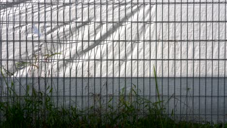 Shadows-of-metal-grid-fence-on-white-plastic-material