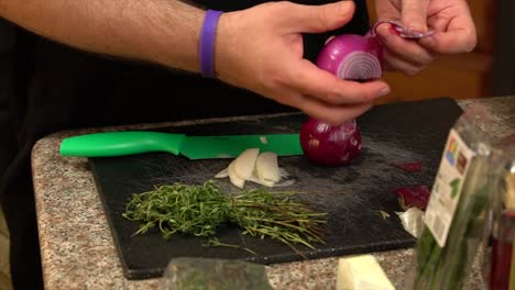 Peeling-a-red-onion-over-a-cutting-board-and-knife