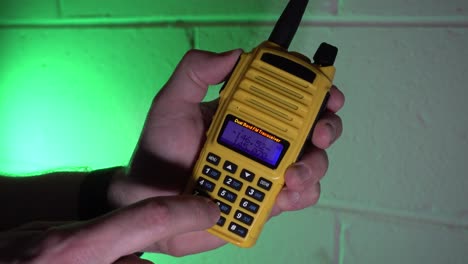Geben-Sie-Eine-Frequenz-In-Ein-Gelbes-Tragbares-Amateurfunkgerät-Ein-Und-Senden-Und-Empfangen-Sie-Dann-Vor-Einem-Grünen-Hintergrund