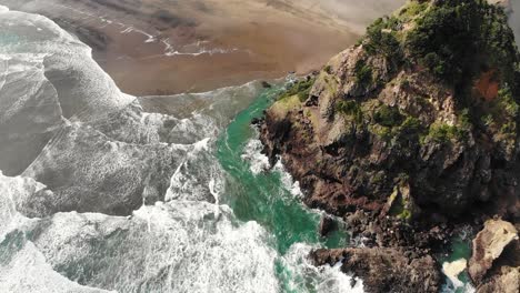 Waves-crash-against-volcanic-Lion-Rock,-Piha-Beach,-New-Zealand