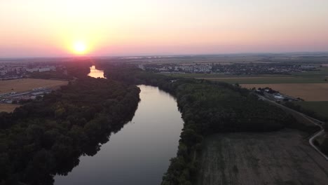 Luftdrohne-über-Einem-Wunderschönen-Fluss,-Umgeben-Von-Getreidefeldern,-Sonnenuntergang-Und-Wasser