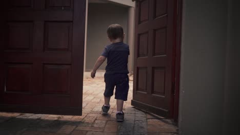 Back-view-of-a-child-running-through-a-wooden-door-frame,-unrecognizable-Caucasian-toddler