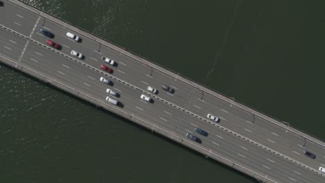 Aerial-zoom-in-busy-road-bridge-highway-directly-over-the-Captain-Cook-Bridge-on-dark-ocean-water-at-Taren-Point,-Sydney-Australia