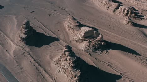 Empty-paved-road-with-sandstone-formations-in-desert-near-alien-base,-aerial-view
