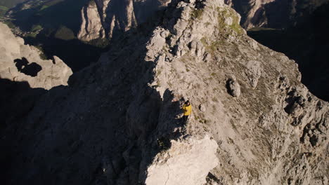 Man-on-precarious-rocky-ledge-overlooking-scenic-valley,-Alps