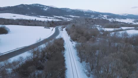 Luftdrohnenansicht-Der-Winterweißen-Schneebedeckten-Schiene-Mit-Dem-Zug,-Der-Sich-In-Richtung-Kamera-Bewegt