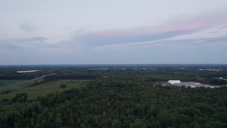Aerial-drone-forward-moving-shot-over-dense-green-forest-trees-on-a-cloudy-evening-time