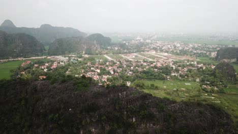 A-aerial-view-ascending-over-a-mountain-reveals-foggy-Tam-Coc-Vietnam