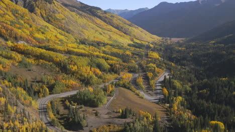 Aerial-shot-panning-up-of-beautiful-Colorado-mountain-roads-and-bright-yellow-and-orange-aspen-trees-during-autumn-in-the-San-Juan-Mountains-along-the-Million-Dollar-Highway-road-trip