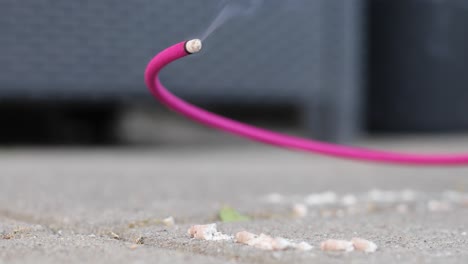 A-pink-burning-wick-of-incense-with-ashes-that-repels-mosquitoes-outside