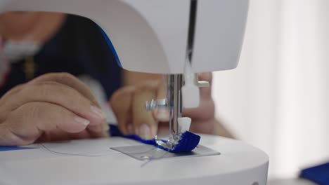 Older-lady-sewing-blue-piece-of-cloth-with-sewing-machine