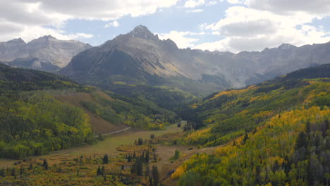Aerial-shot-forward-of-beautiful-Colorado-mountains-and-bright-yellow-and-orange-aspen-trees-during-autumn-in-the-San-Juan-Mountains-showing-fall-landscapes-near-Mt