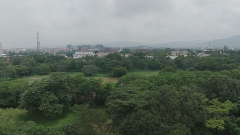 AERIAL---forested-area-under-a-cloudy-sky,-Abuja,-Nigeria,-forward-tilt-up-reveal