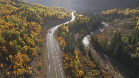 Aerial-shot-forward-of-beautiful-Colorado-mountain-roads-and-bright-yellow-and-orange-aspen-trees-during-autumn-in-the-San-Juan-Mountains-along-the-Million-Dollar-Highway-road-trip
