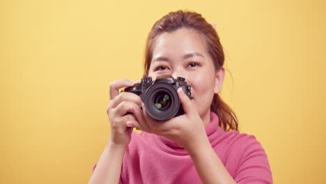 Wunderschöne-Junge-Asiatische-Frau-In-Einem-Studio,-Das-Mit-Einer-Digitalkamera-Mit-Kopierraum-Für-Werbung-über-Einem-Isolierten-Gelben-Hintergrund-Gedreht-Wurde-1