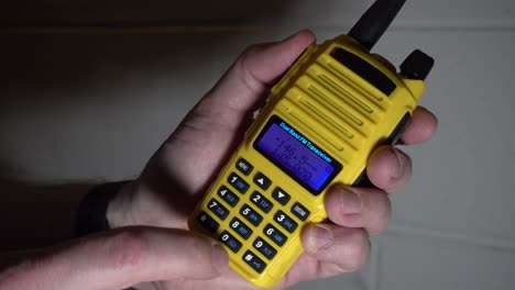 Geben-Sie-Eine-Frequenz-In-Ein-Gelbes-Tragbares-Amateurfunkgerät-Ein-Und-Senden-Und-Empfangen-Sie-Dann-Vor-Einem-Blinkenden-Roten-Hintergrund