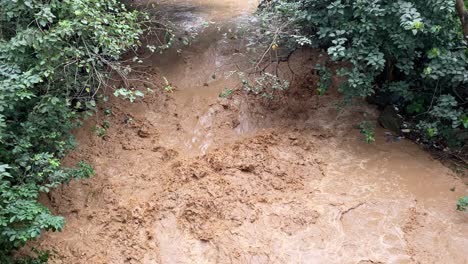 AERIAL---Very-muddy-river,-brown-rushing-water,-Abuja,-Nigeria,-tilt-up-reveal