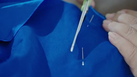 Cutting-blue-cloth-with-tailoring-scissors-near-stitched-line