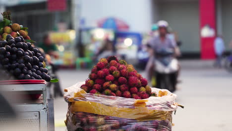 Lychee-and-grapes-being-sold-at-street-stall-next-to-busy-street-in-Southeast-Asia