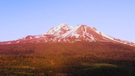 A-reverse-drone-shot-shows-a-pink-hue-covering-Mount-Shasta-in-California