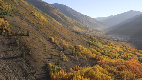 Aerial-shot-panning-right-of-beautiful-Colorado-mountain-towns-and-bright-yellow-and-orange-aspen-trees-during-autumn-in-the-San-Juan-Mountains-along-the-Million-Dollar-Highway-road-trip