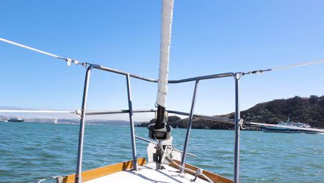 Pov-Von-Der-Vorderseite-Eines-Segelboots,-Während-Die-Wellen-Das-Boot-In-Der-Bucht-Von-San-Francisco-Mit-Der-Golden-Gate-Bridge-Im-Hintergrund-An-Einem-Sonnigen-Tag-In-4k-Vor--Und-Zurückschaukeln