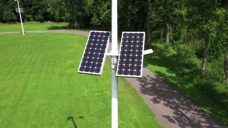 Renewable-energy-point-of-solar-panel-and-wind-turbine-on-light-pole,-aerial-reveal