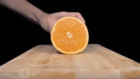 An-orange-fruit-is-put-on-a-board-and-cut-into-a-slice-in-slow-motion,-UHD