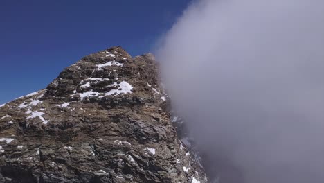 Gipfel-Des-Mount-Cervino,-Das-Matterhorn,-Mit-Wolken,-Die-Ein-Gesicht-Und-Blauen-Himmelshintergrund-Bedecken