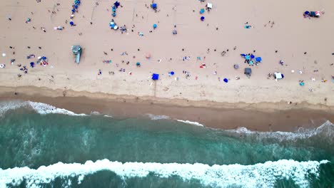 Tropical-sandy-Manhattan-beach-with-ocean-waves-hitting-coastline,-aerial-birds-eye