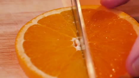A-slice-of-orange-being-cut-in-slow-motion,-UHD